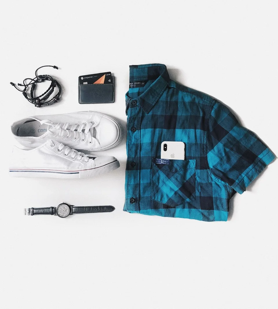 Folded blue checked shirt arranged with everyday accessories