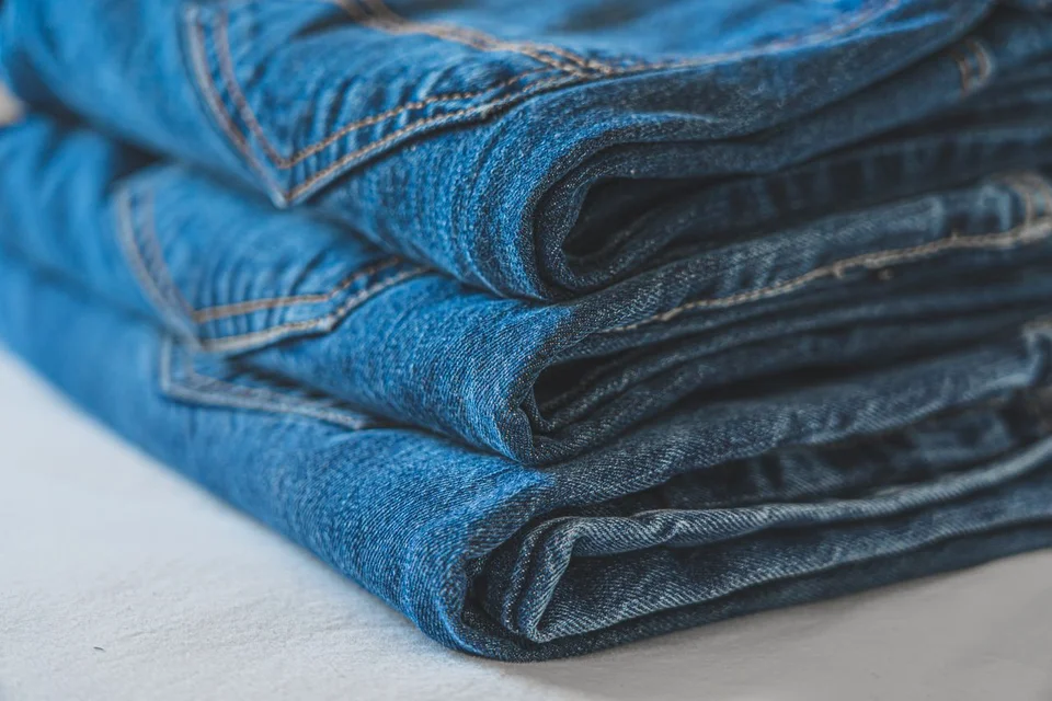 Neatly folded blue jeans with visible pockets and stitching
