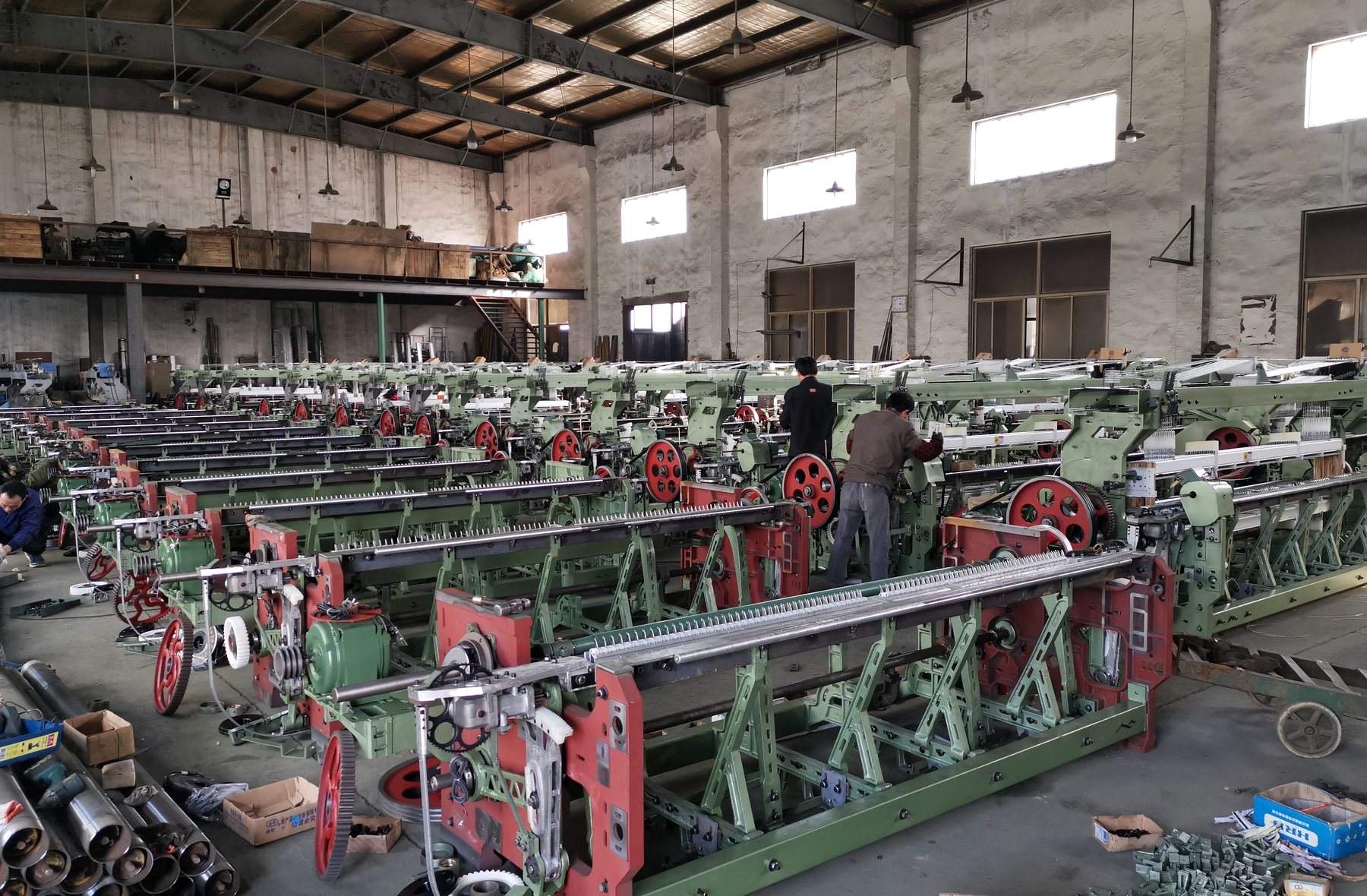 Rows of rapier looms being assembled in a textile machinery workshop